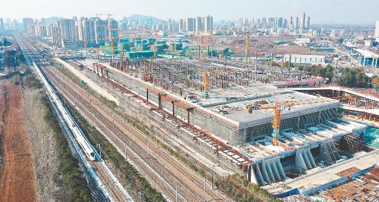 2025年1月16日,高速列车从合肥西站建设现场一旁驶过。项目工地上车辆穿梭,施工人员正在进行紧张的施工作业。
