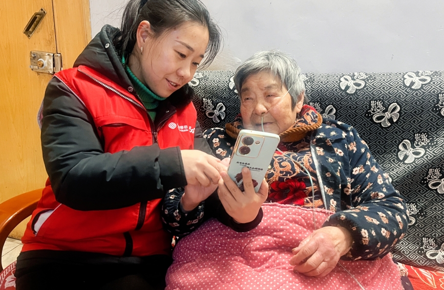 湖北移动志愿者正细心地教老人使用手机，暖心服务助“银发族”跨越数字鸿沟